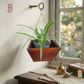 Hanging wooden planter with a plant next to a window with a garden view.