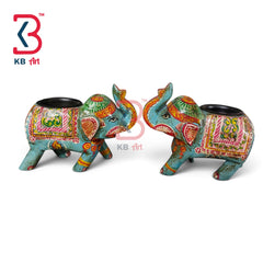 Two decorative elephant-shaped candle holders with colorful hand-painted patterns in turquoise, green, orange, pink, and red, set against a plain white background with a KB Art logo in the top left corner.