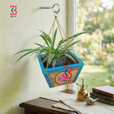 KB ART traditional hand-painted colorful wooden hanging planter and artistic wall pot featuring floral mandalas and a turquoise-blue rim holding a green spider plant suspended by a golden chain.