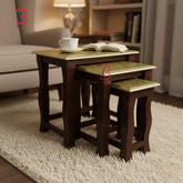 Set of three wooden nesting tables with gold leaf accents in a living room setting.