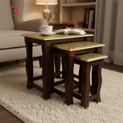 Set of three wooden nesting tables with gold leaf accents in a living room setting.