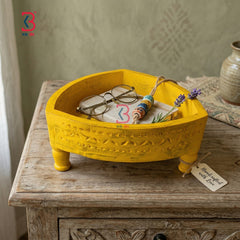 Real product photograph on a white background showing a distressed yellow handmade triangular wooden carved chakki table by KB Art.