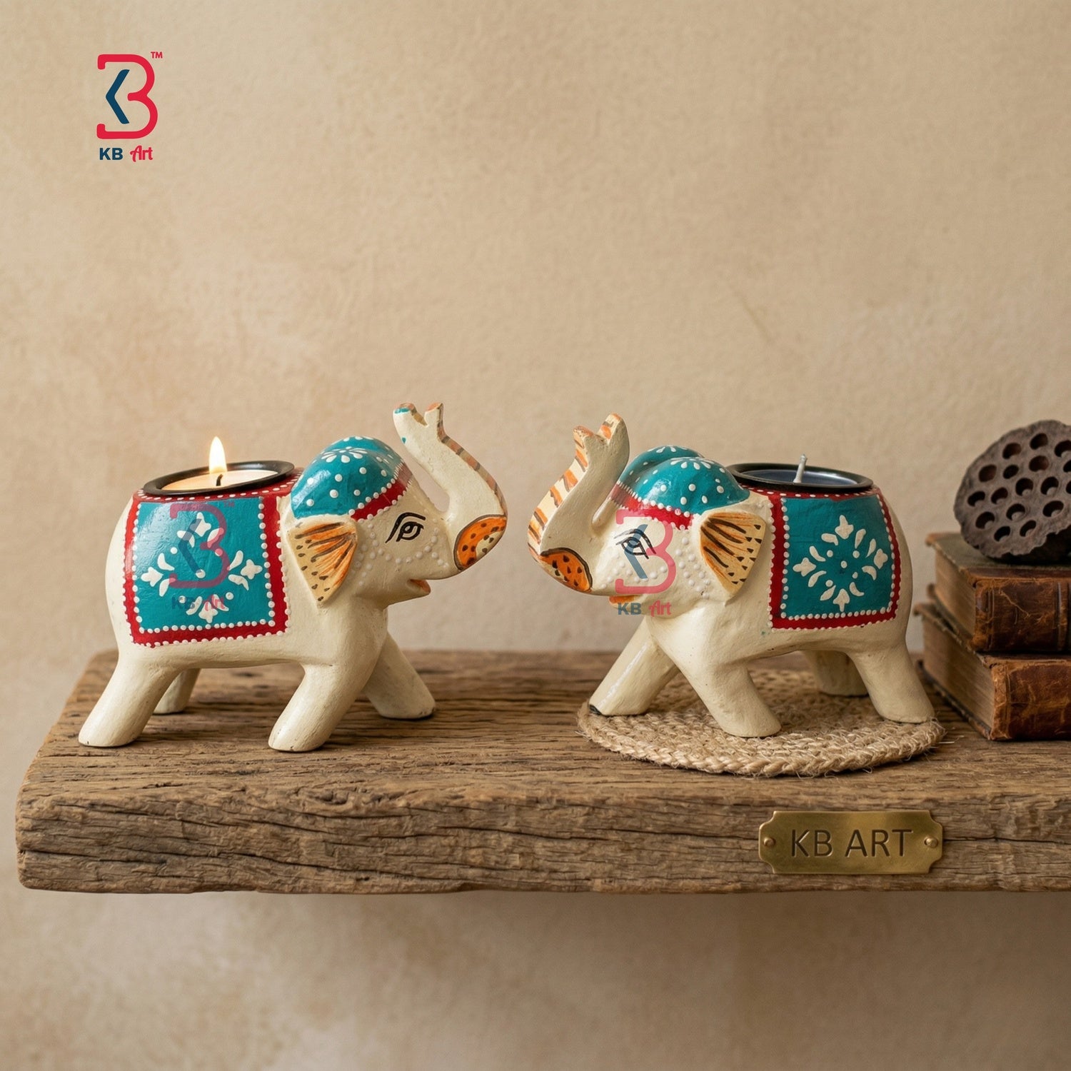 KB ART pair of ethnic hand-painted wooden elephant tea-light candle holders with teal and red blankets on an antique white-wood body against a white background.