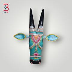 Hand-painted wooden cow head wall decor in turquoise with black horns and vibrant floral patterns.