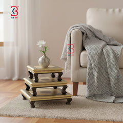 Three-tiered wooden side table with a vase of flowers in a living room setting.