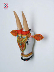 Ethnic carved wooden bull head decor, featuring intricate patterns and vibrant colors on a white background.