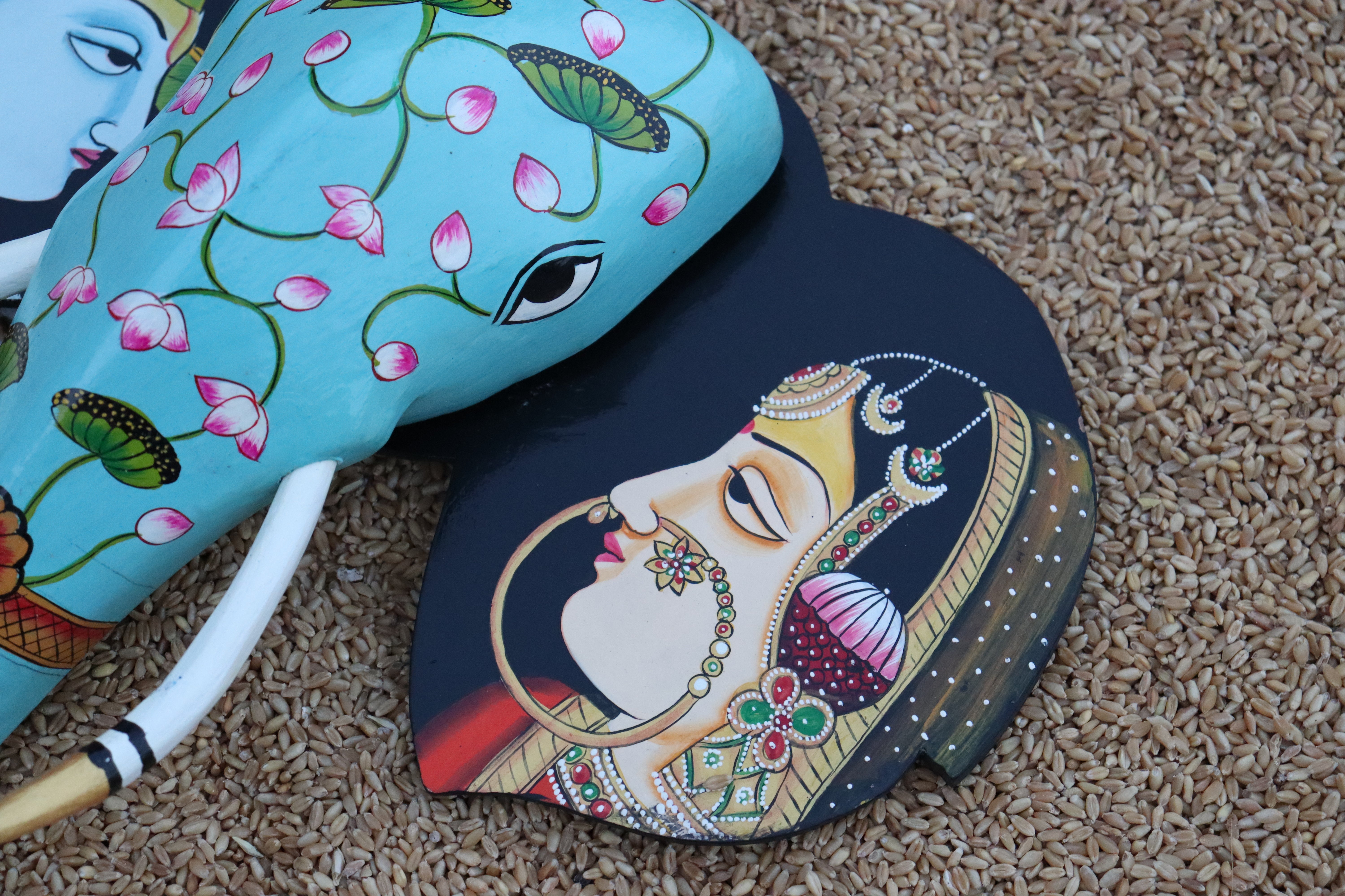 Colorful Indian elephant head sculpture for wall decor, with detailed face paintings on the ear flaps.