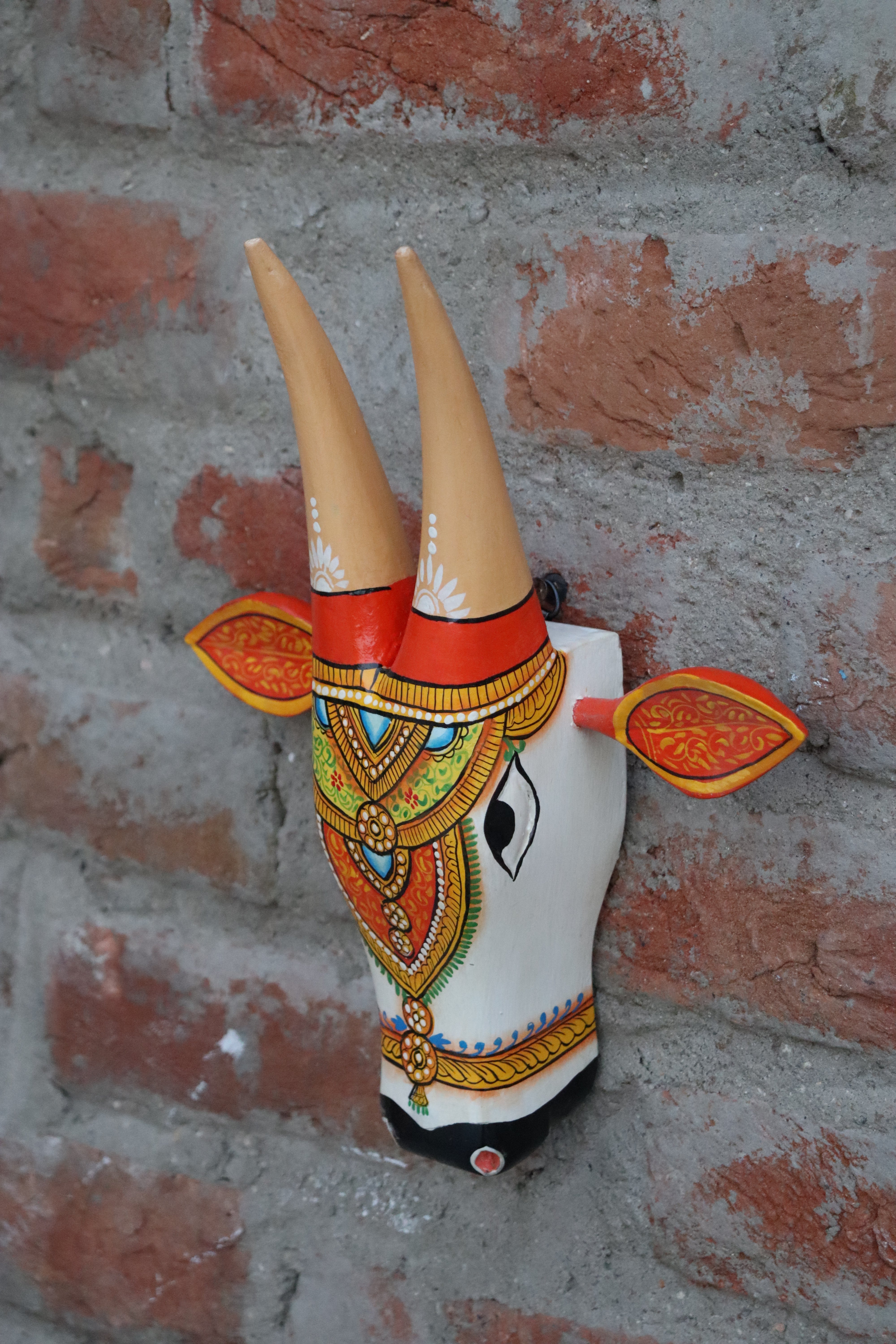 Handcrafted wooden cow mask with ornamental design and realistic eyes, ideal for wall decoration.