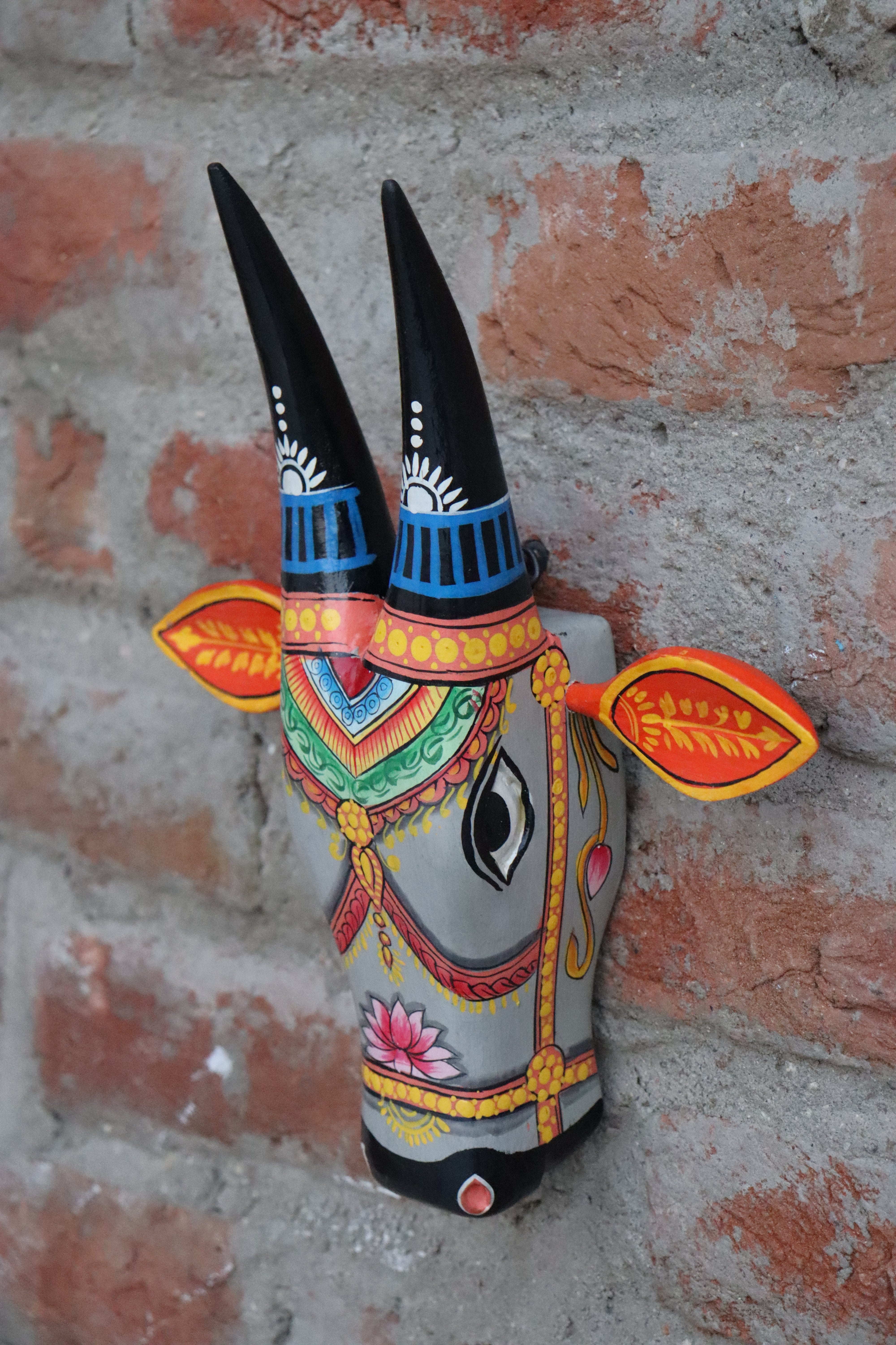 Ornate wooden cow wall hanging with detailed eyes, horns, and ears on a gray background.