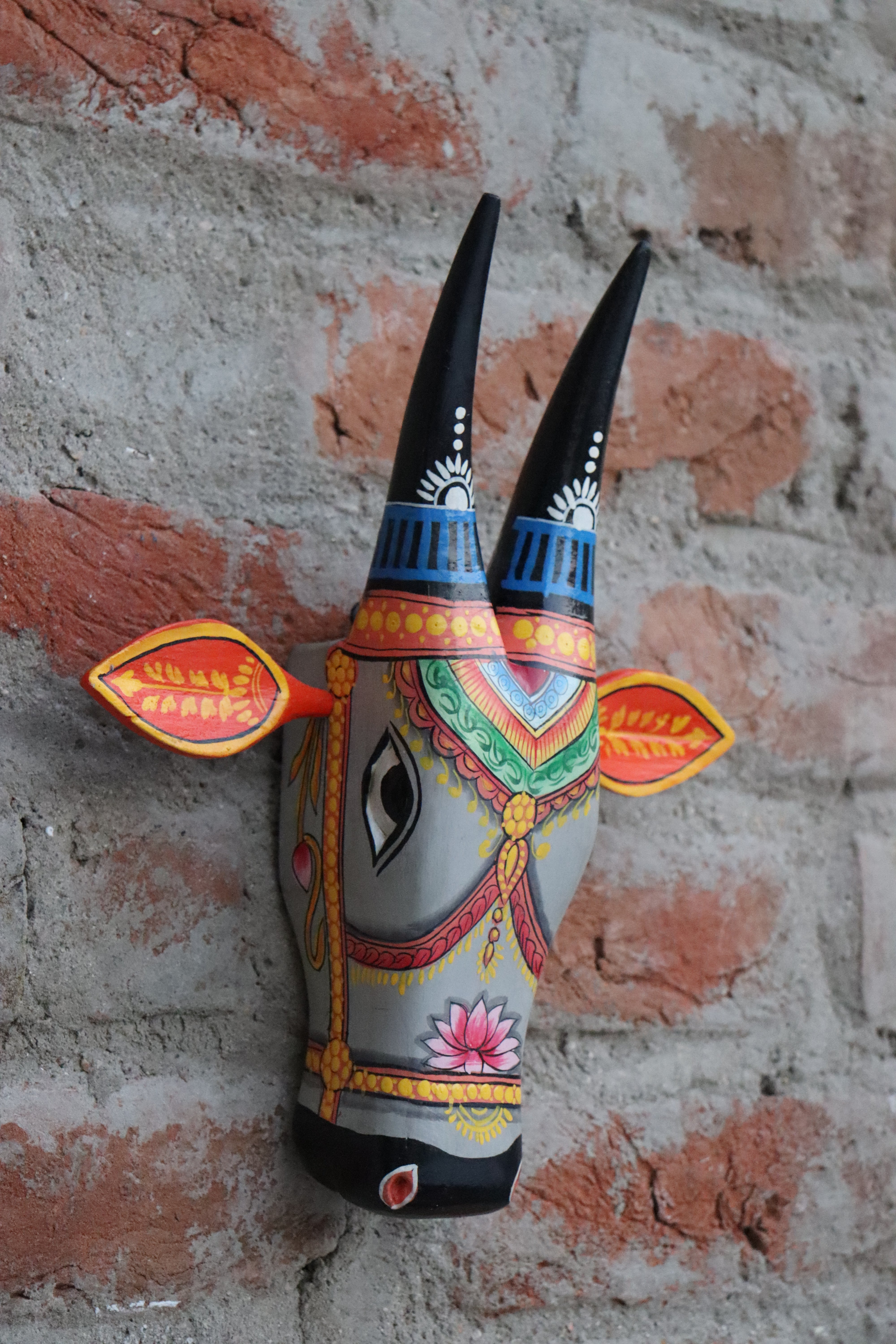 Handmade wooden cow head with vibrant colors and bold patterns, ideal for a wall hanging.