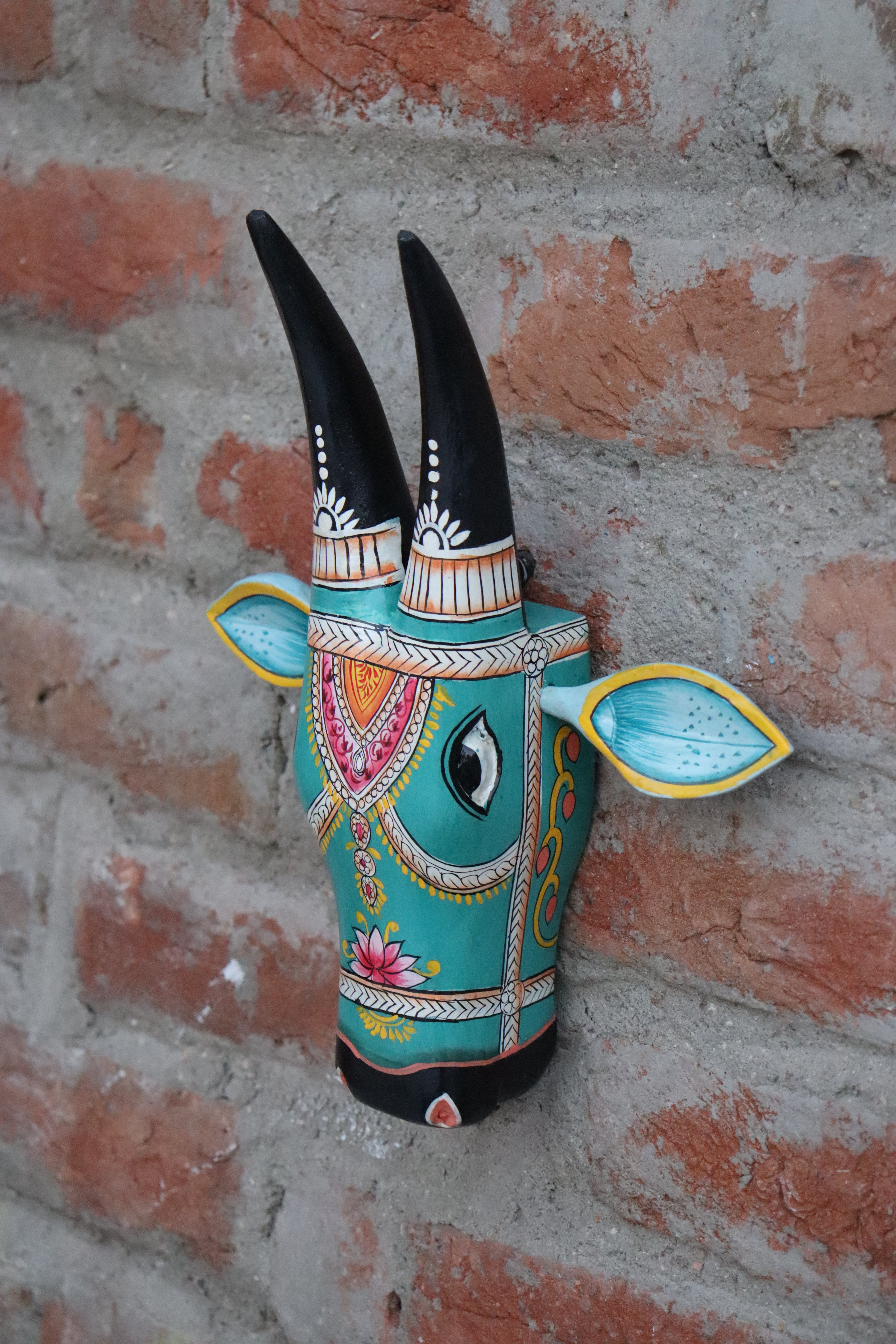 Handcrafted wooden cow bust featuring elaborate patterns and a distinctive design on a rustic background.