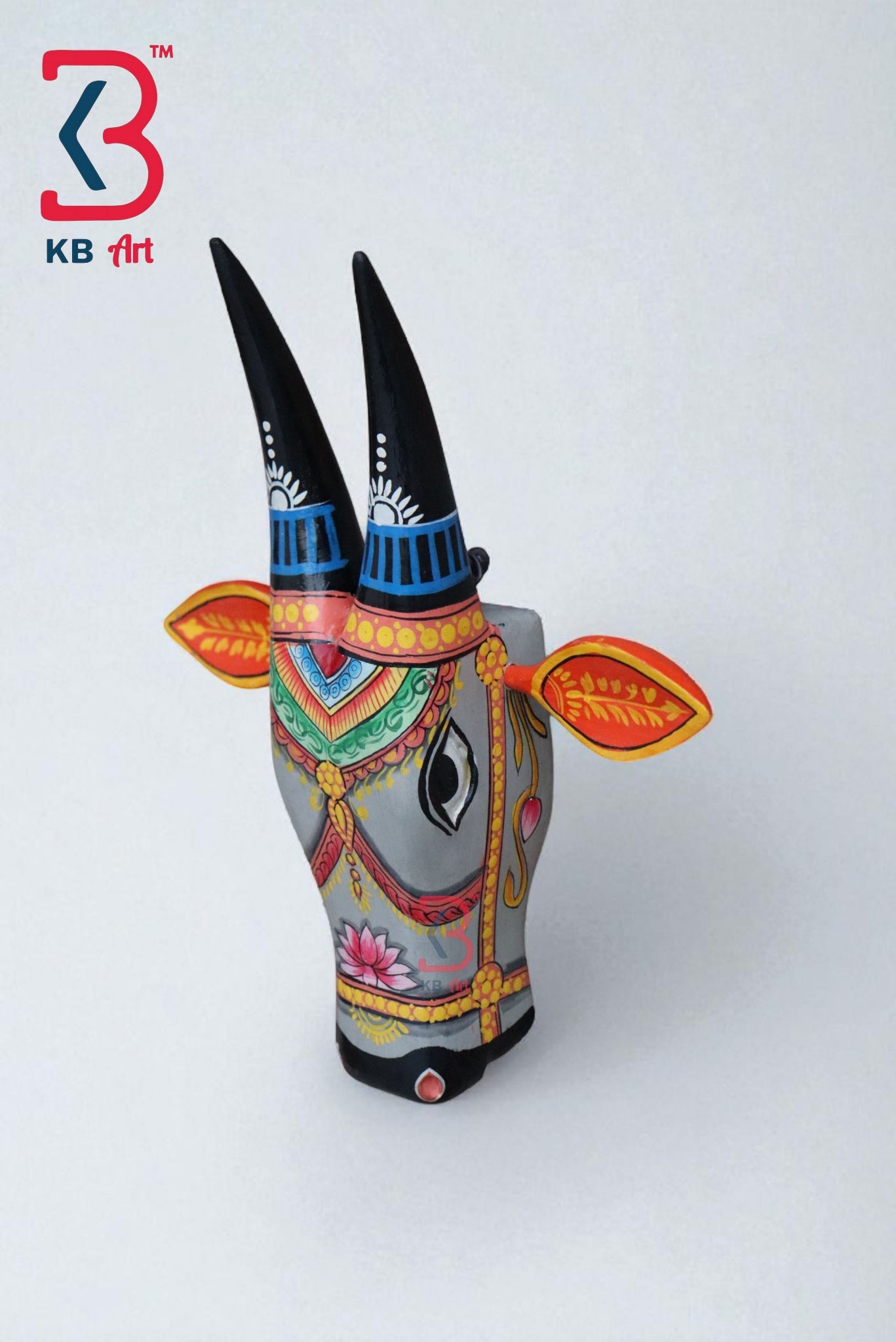 Decorative gray wooden bull head mask featuring traditional Indian patterns and a pink lotus flower.