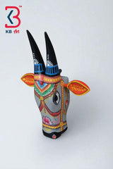 Decorative gray wooden bull head mask featuring traditional Indian patterns and a pink lotus flower.