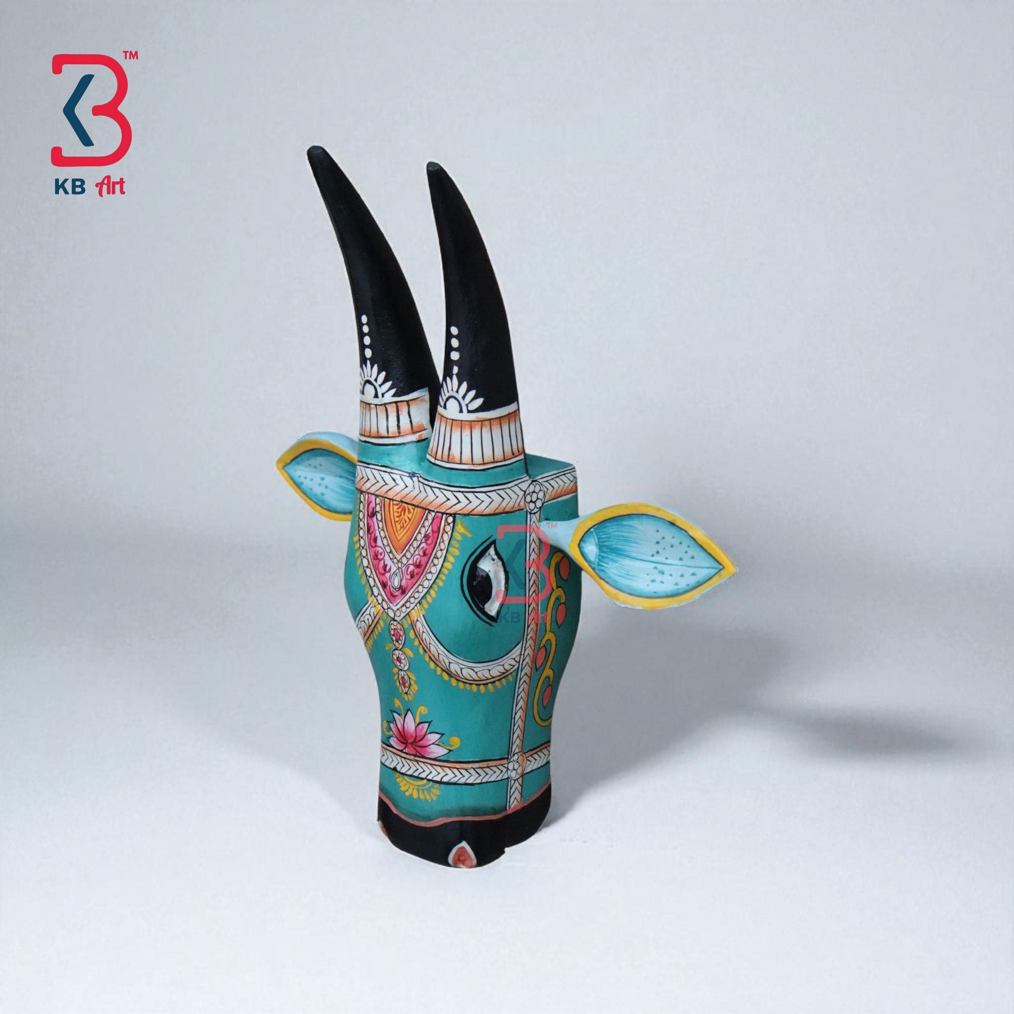 Ornate wooden cow wall hanging with painted ears in light blue and yellow, and decorative white dots on horns.