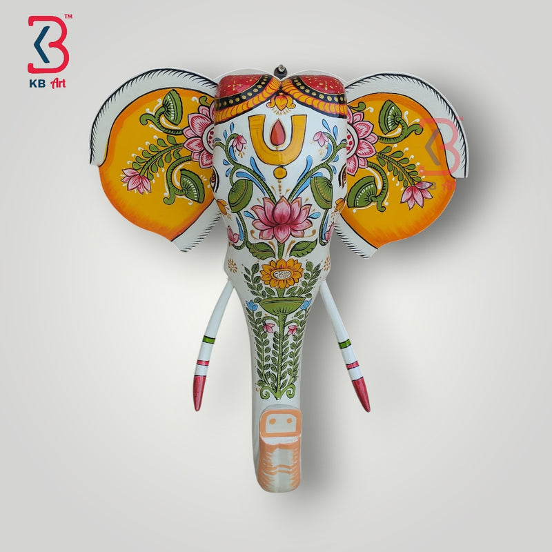Decorative carved wooden elephant head with large ears and a decorated trunk, showcasing cultural craftsmanship.