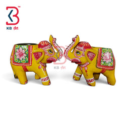 Two decorative elephant figurines painted in bright yellow with red, pink, green, and white floral and geometric patterns, shown on a white background with a KB Art logo in the top left.