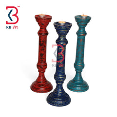 Three distressed wooden candlesticks in red, blue, and teal, each holding a tealight candle, displayed on a white background with a KB Art logo in the top left.