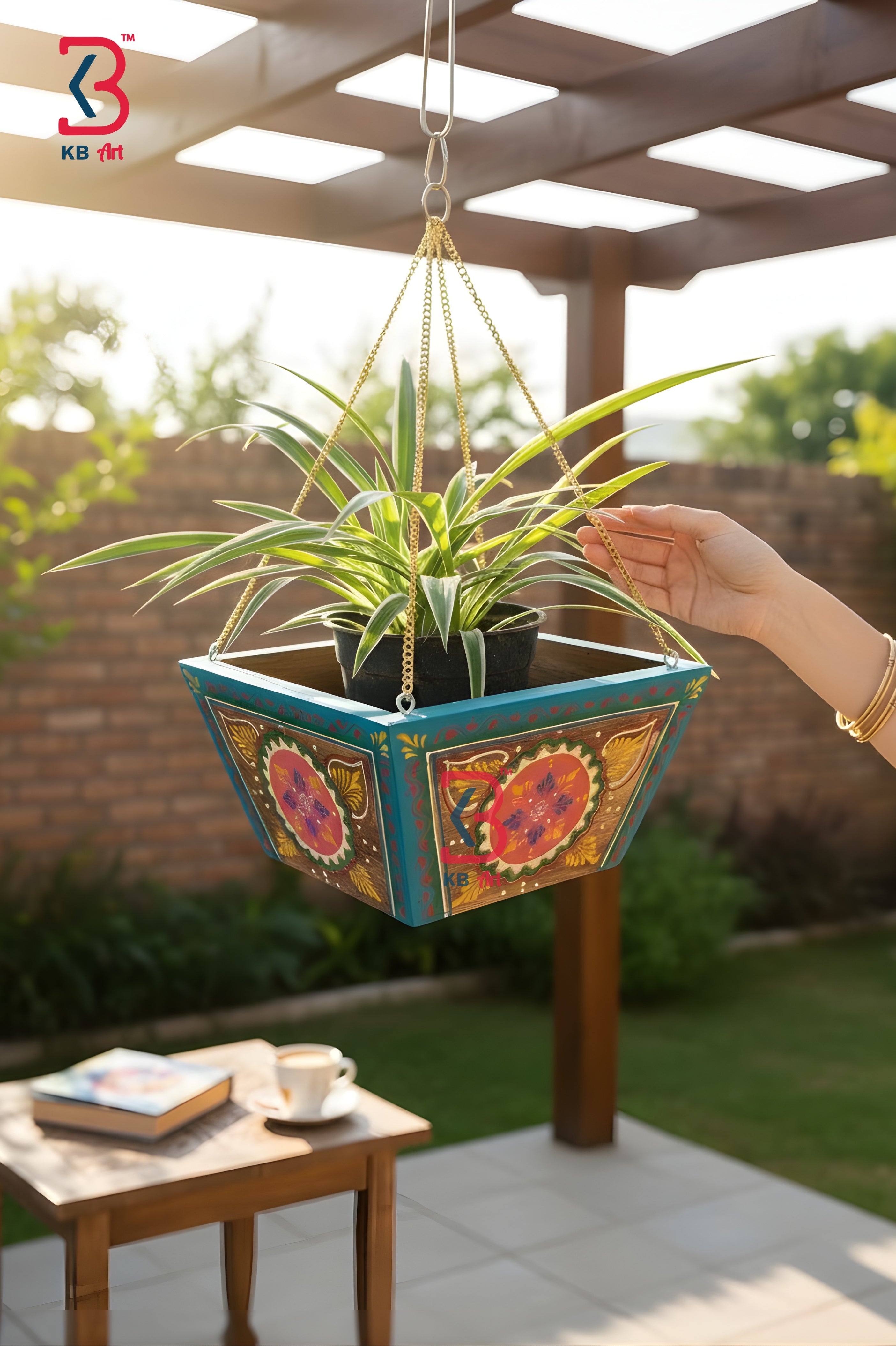 Hanging planter with colorful floral design held by a hand outdoors.