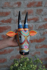 Ethnic carved wooden cow head with ornate craftsmanship and a detailed floral motif.