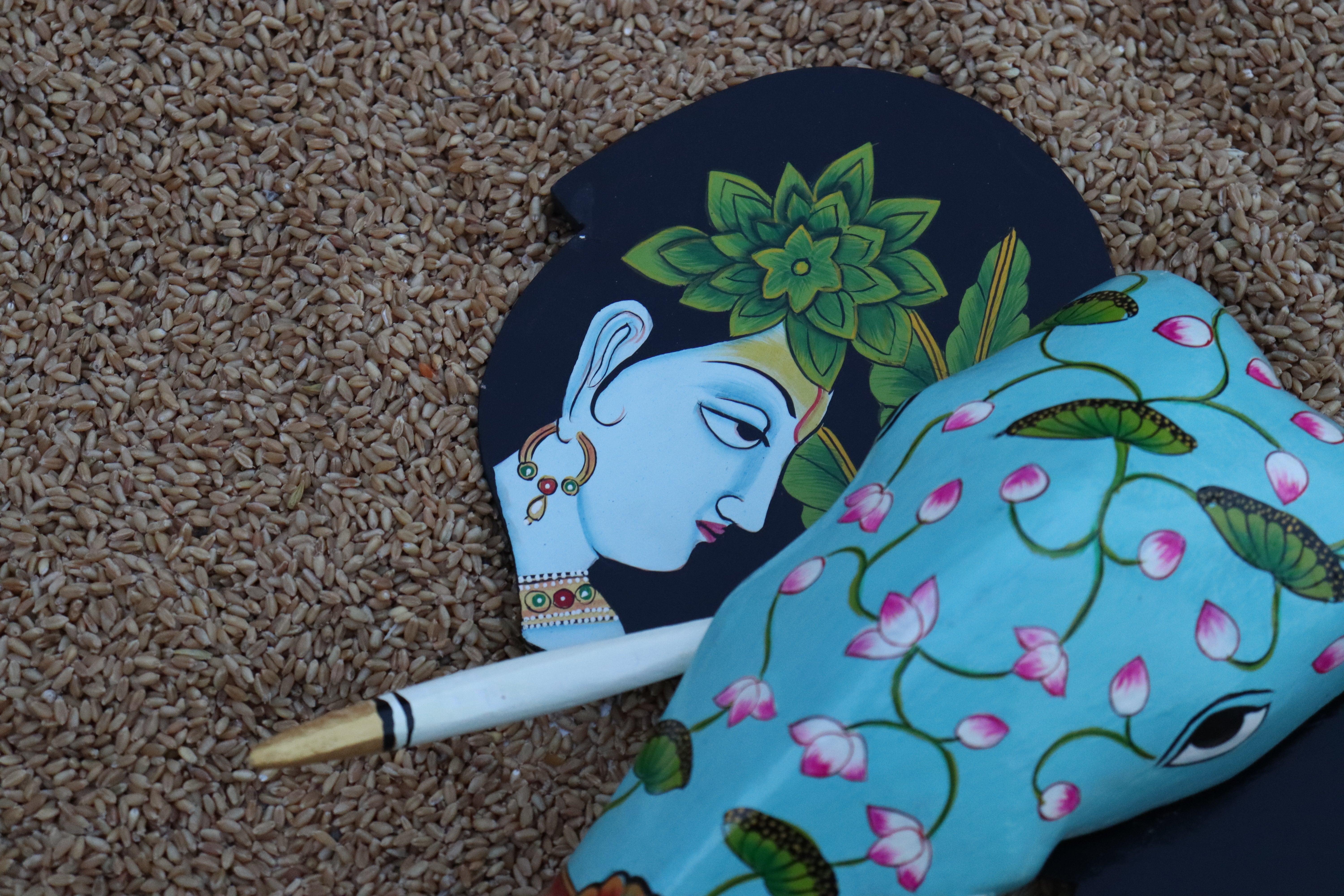 Traditional wooden elephant bust with a floral-patterned trunk and elegant portraits on the side ears.