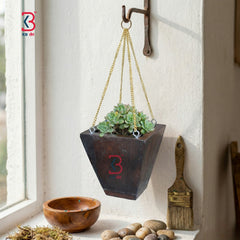 KB ART rustic wood planter and minimalist tapered hanging wall planter box holding a green succulent plant suspended by a golden metal chain against a white background.