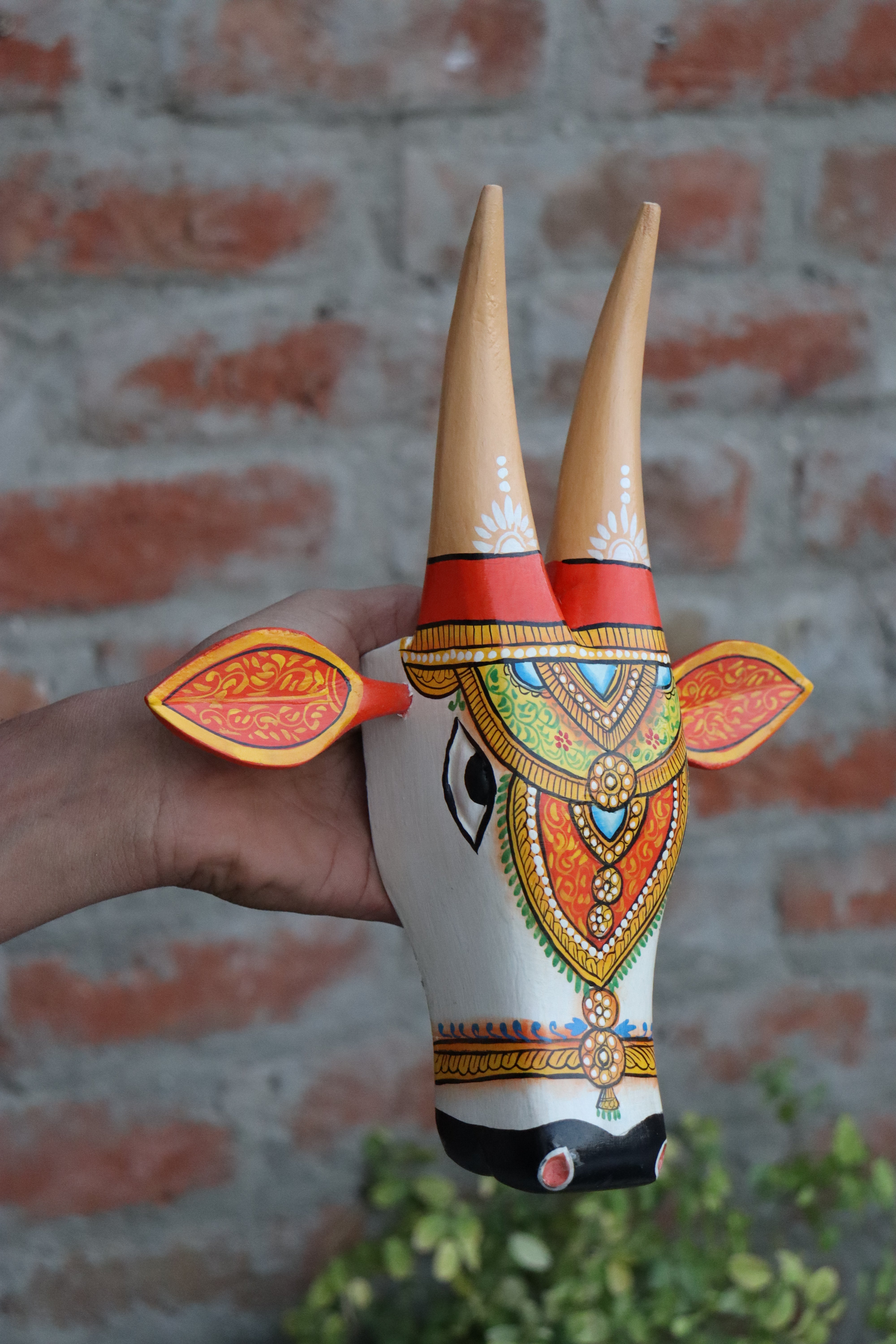 Decorative wooden cow head with sculpted horns and ears, a handmade artifact for wall accents.