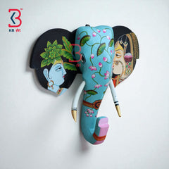 Decorative wooden elephant head showcasing traditional Indian art, including a man and woman painted on the ears.