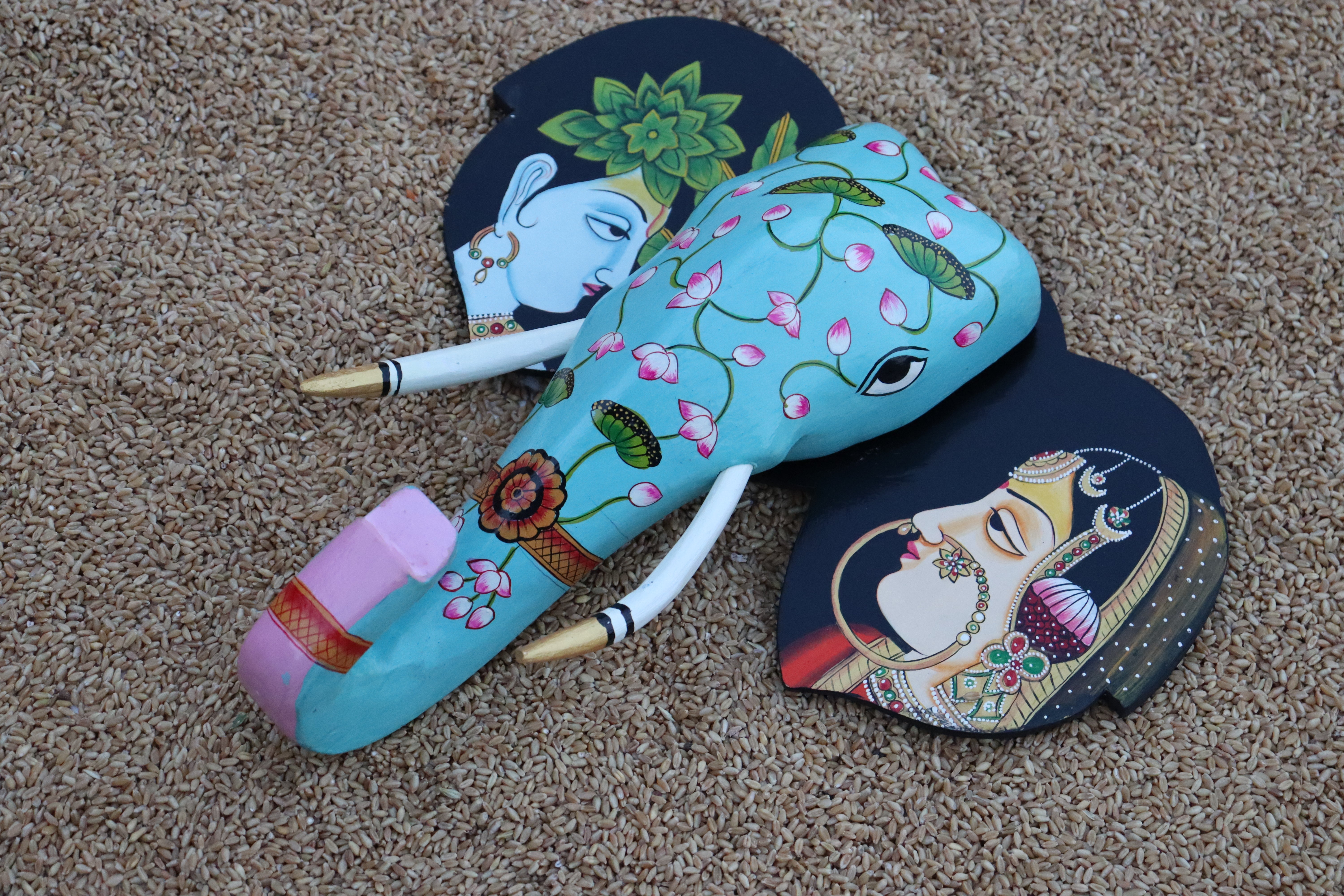 Artistic wooden elephant wall decor featuring painted depictions of a Radha and Krishna on the ears.