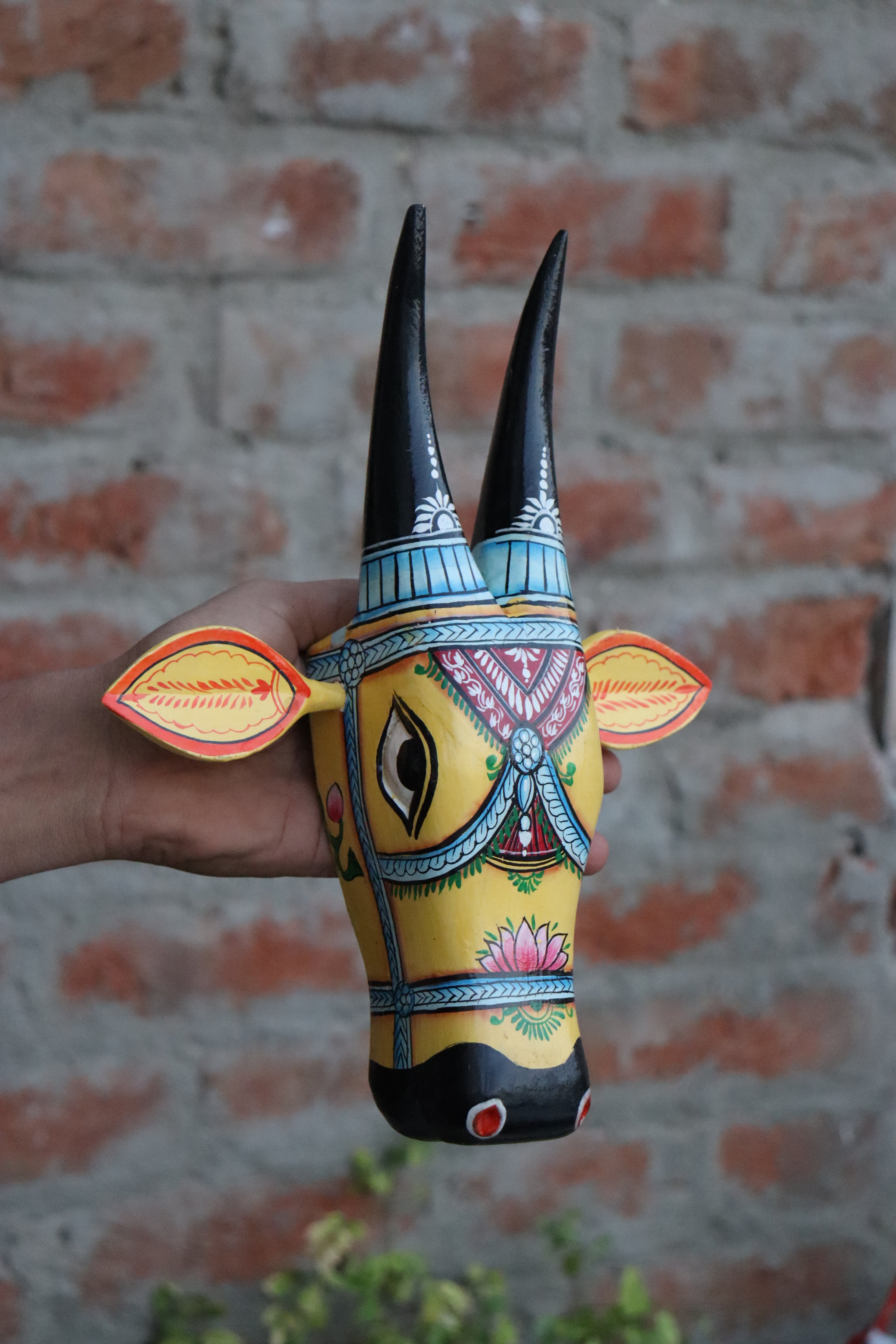 Decorative wooden cow head wall art featuring traditional Indian designs and long horns.