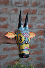 Decorative wooden cow head wall art featuring traditional Indian designs and long horns.