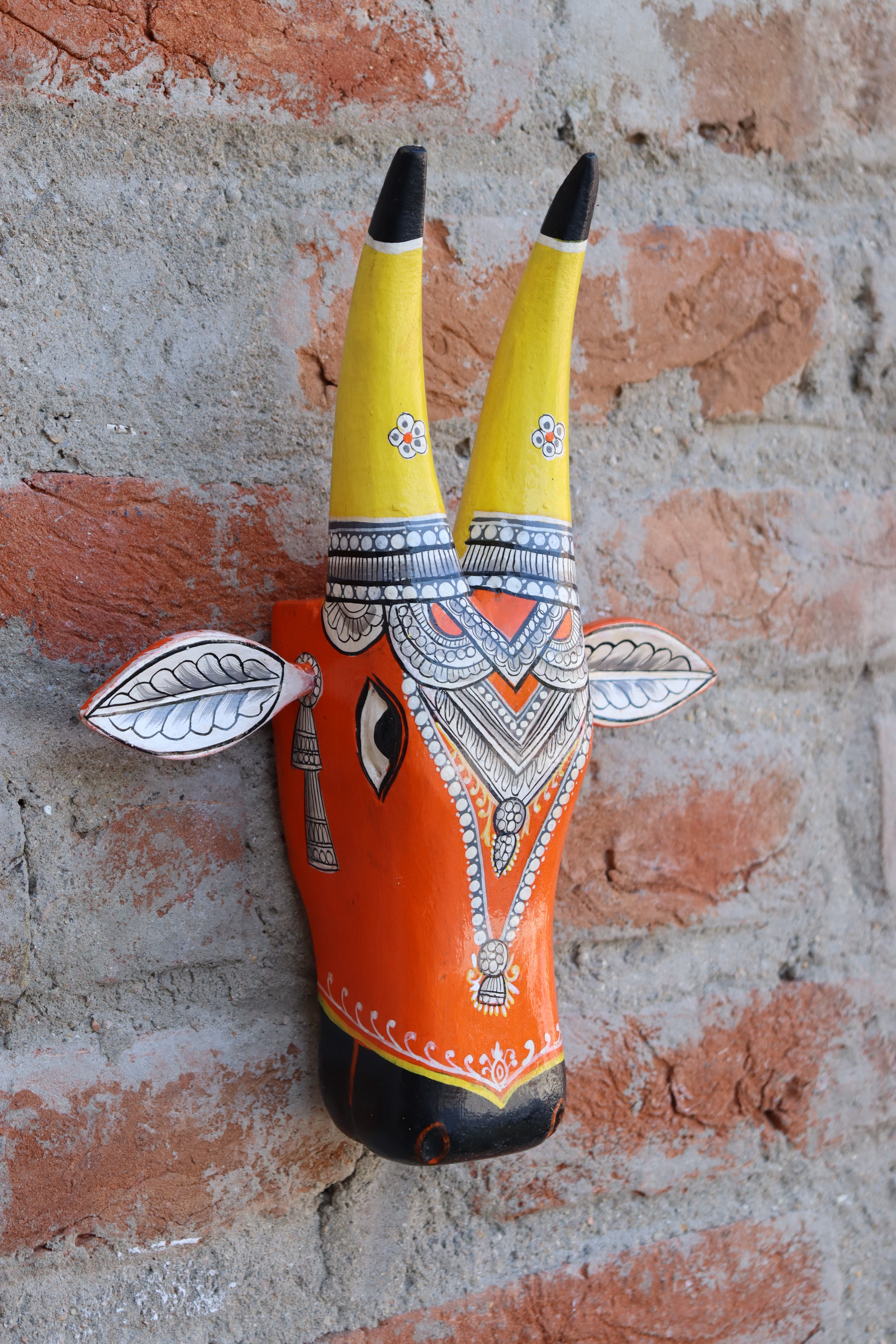 Unique carved wooden cow head wall hanging, painted with bold colors and ornamental motifs.