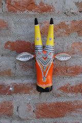 Handcrafted wooden cow bust featuring a striking orange and yellow color scheme with detailed craftsmanship.