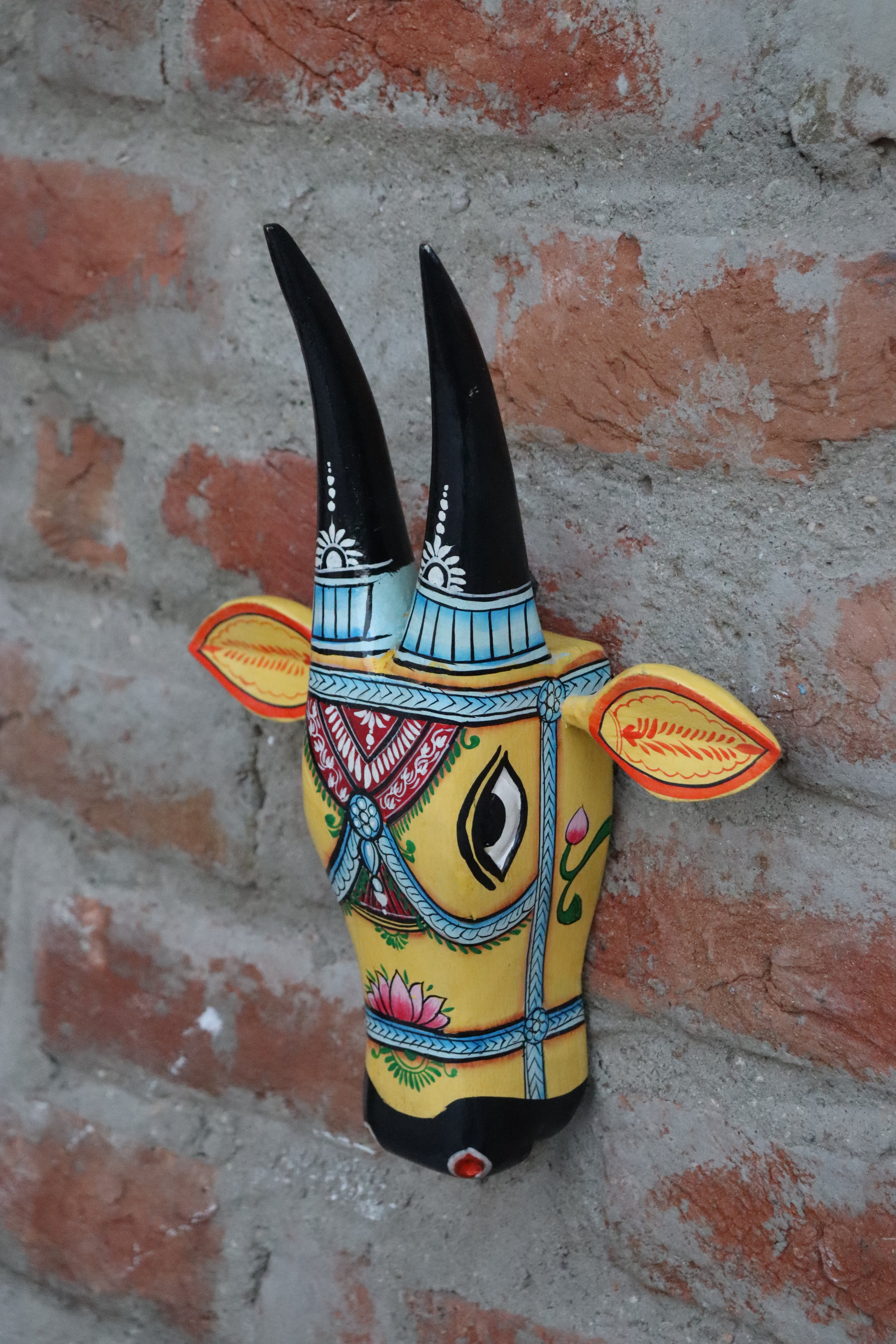 Decorative wooden cow head with sculpted horns and ears, a handmade artifact for wall decoration.