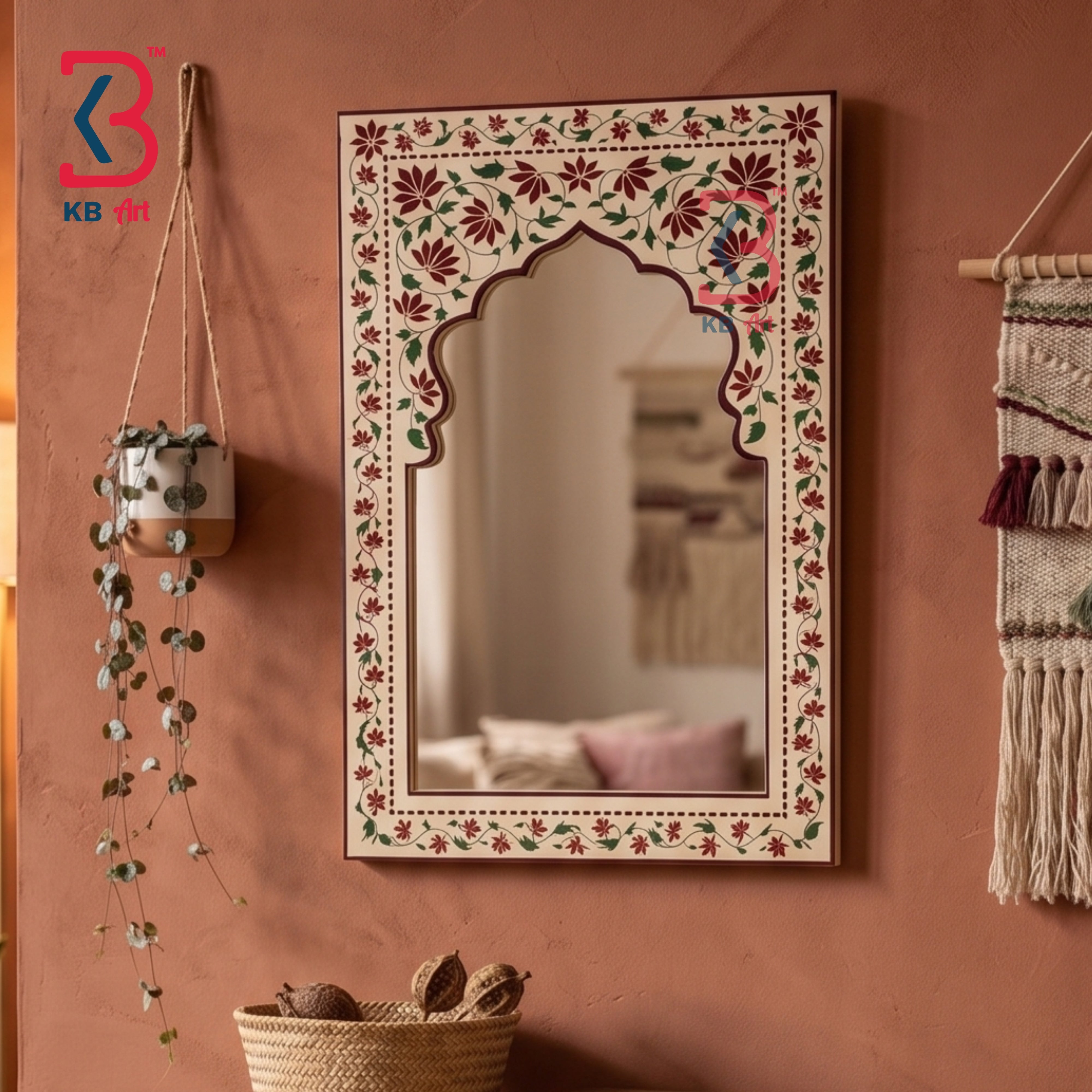 An ornate rectangular wall mirror with a floral hand-painted border and an arched central opening, mounted on a terracotta-colored wall. The mirror reflects a softly blurred interior scene.