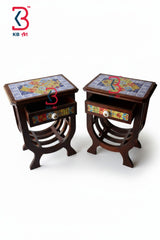 A pair of dark brown wooden side tables with colorful mosaic tile tops and drawer fronts, set against a plain white background. A KB art logo is visible in the top left corner.