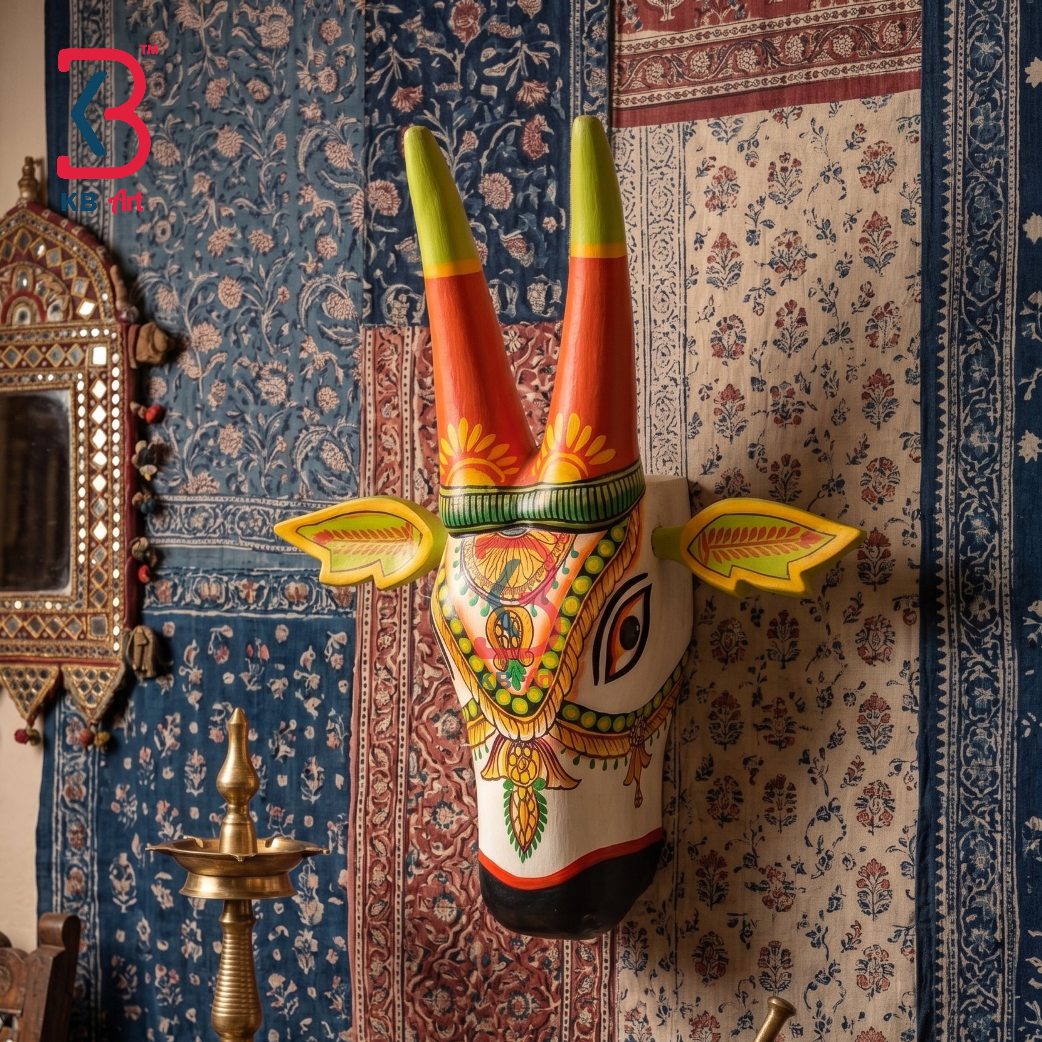 A hand-painted traditional Indian Golu wall decoration depicting a stylized cow head with tall red and green horns, mounted on a patterned blue and beige rug.