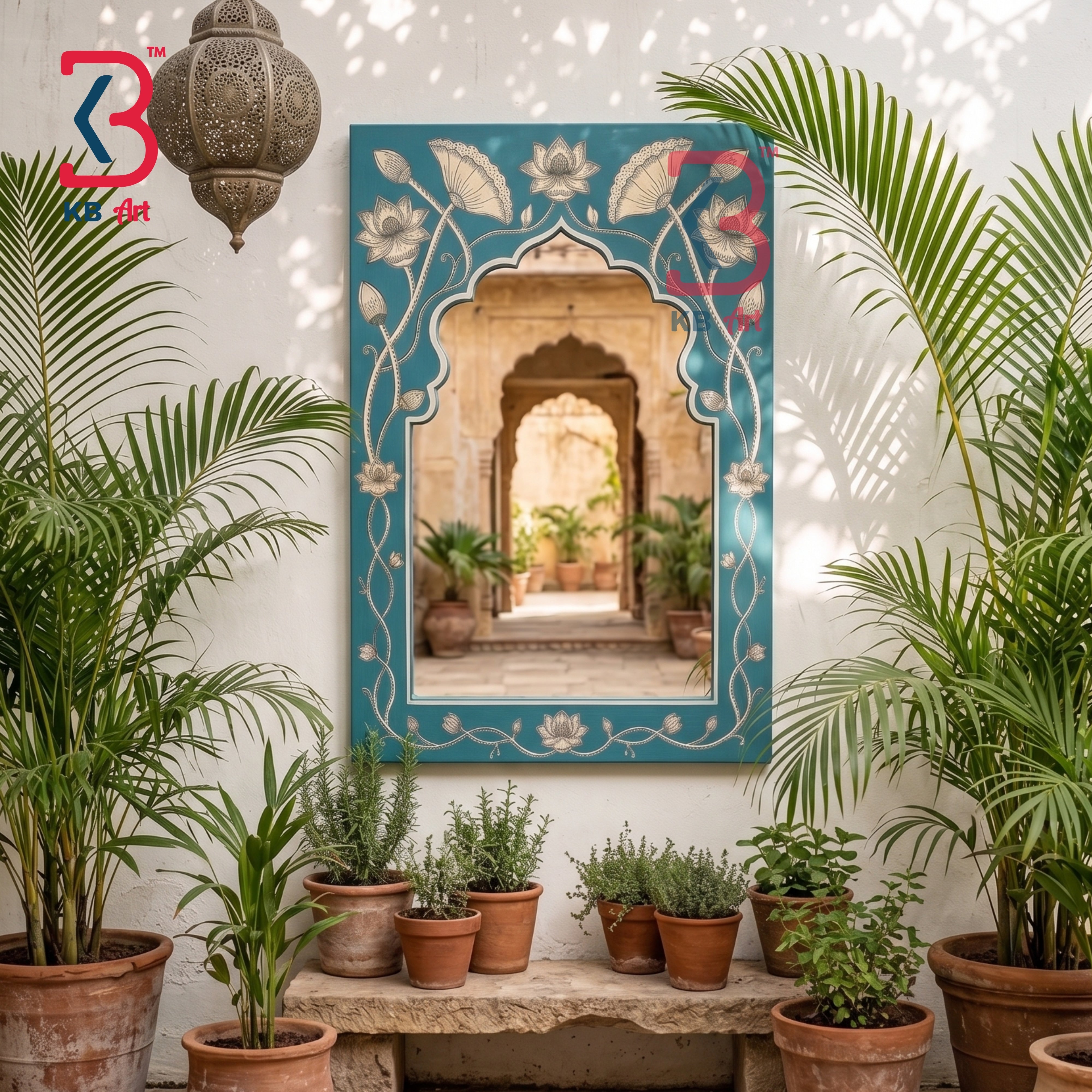 A decorative rectangular wall mirror with an ornate turquoise border and floral motifs, mounted on a white wall in a styled courtyard setting with potted plants and a hanging lantern.