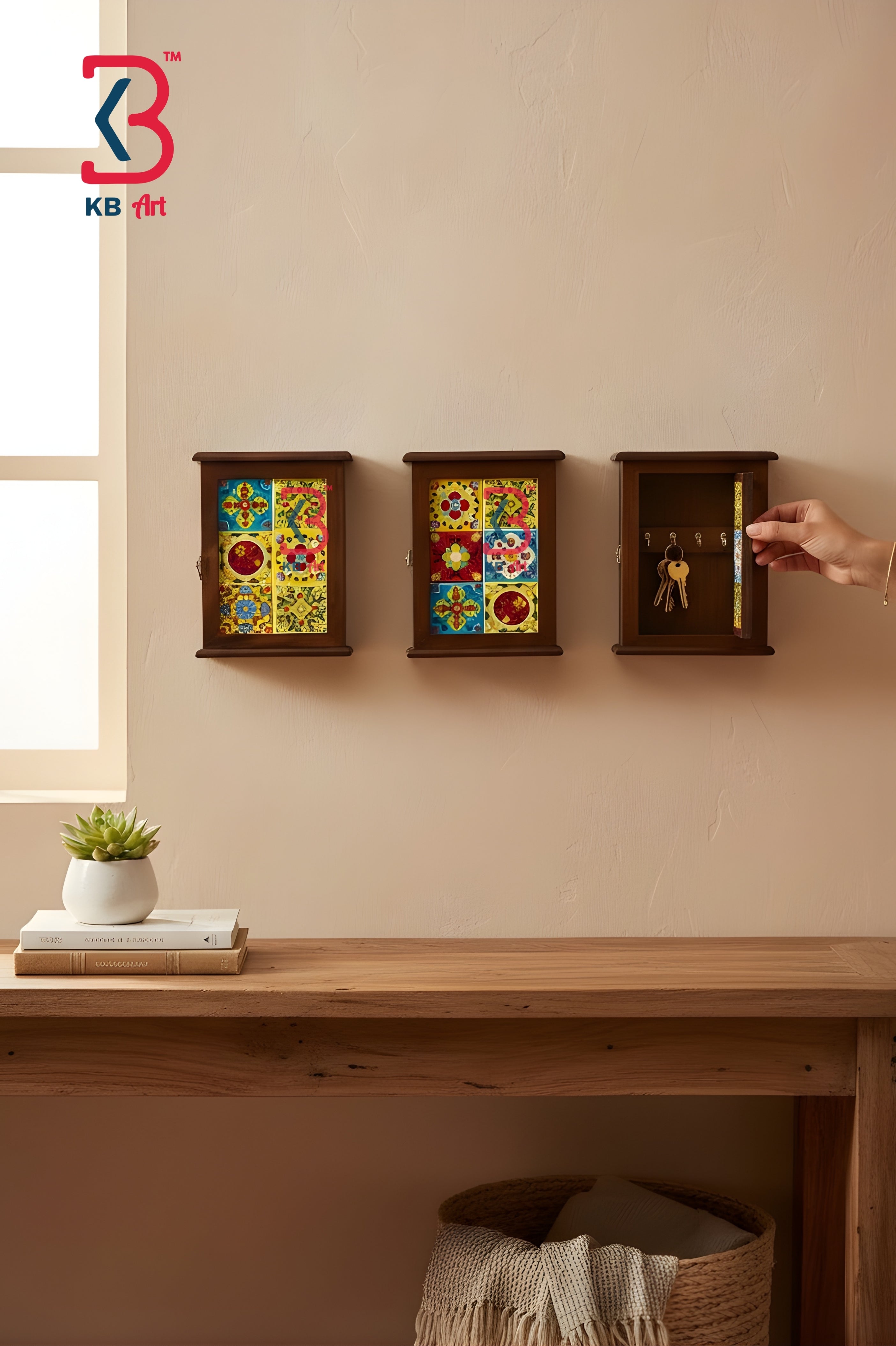 Three small dark wood wall-mounted decorative boxes are shown on a beige wall above a wooden table. Two boxes have colorful mosaic-style panels, and the right box is open with a hand turning a key, revealing gold-toned interior compartments.