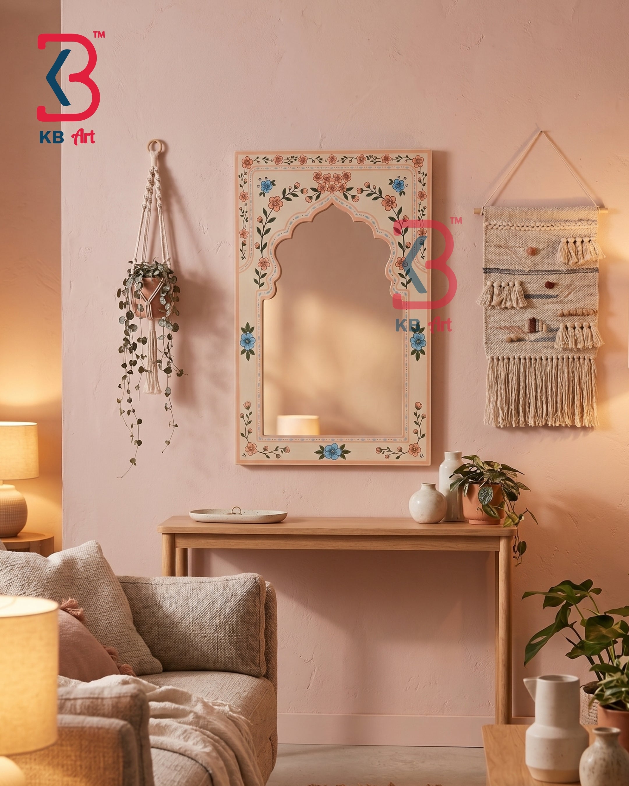 A decorative arched wall mirror with a floral hand-painted frame hangs on a pink wall above a wooden console table in a cozy living room setting.