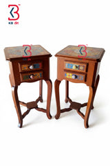 A pair of small wooden side tables with two drawers each, featuring colorful hand-painted floral patterns on the tabletops and drawer fronts, set against a plain white background.