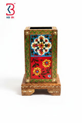 A square wooden desk organizer with a carved base, decorated with traditional hand-painted floral motifs in red, green, yellow, and blue on a white background.